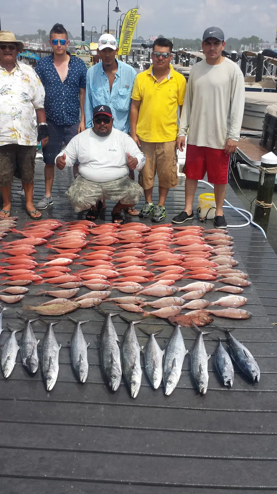 Anglers posing with king mackerel and red snapper on the dock